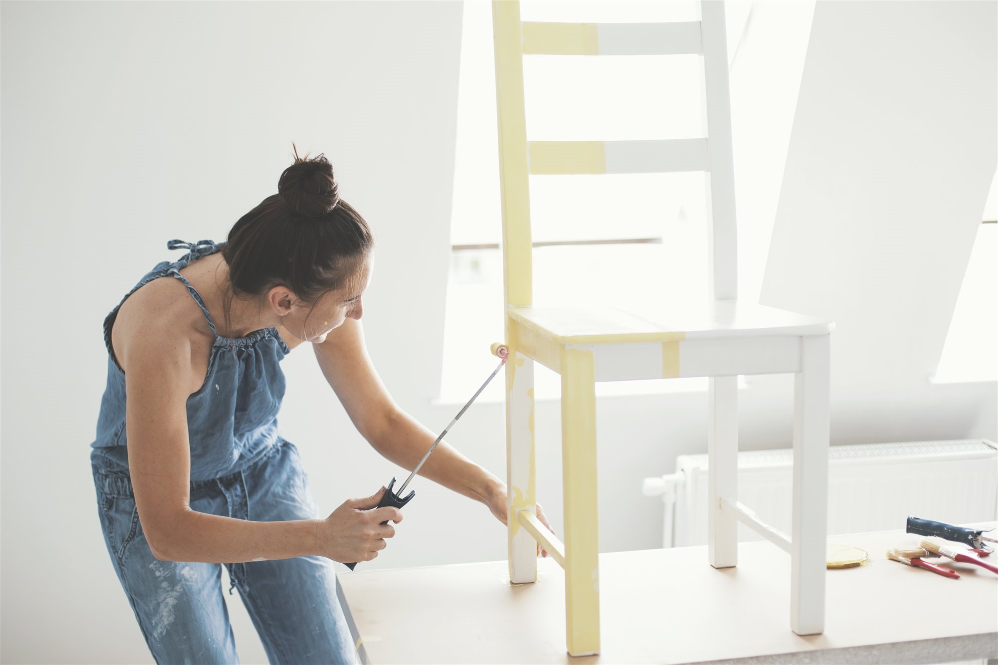 Mujer pintando una silla con rodillo