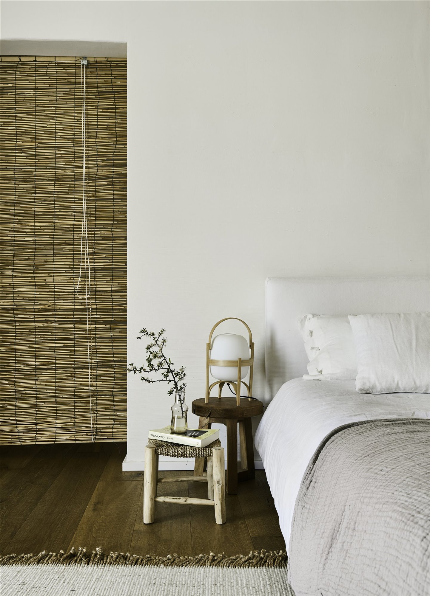 Dormitorio con suelos de madera y cabecero de tela en color blanco