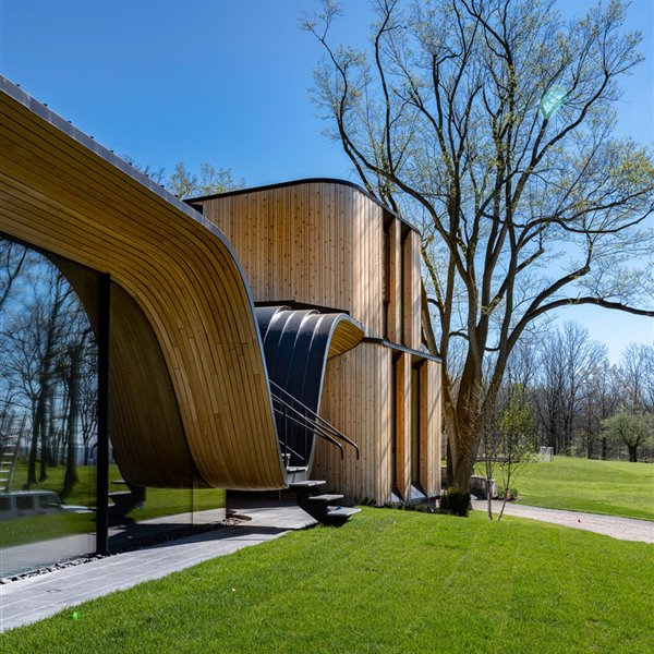 Una casa moderna con fachada de madera curvada en los bosques de Canadá