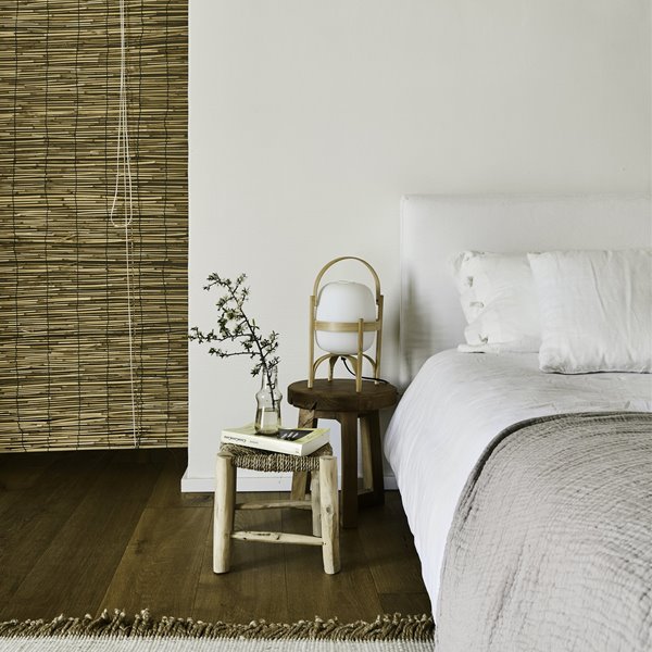 Dormitorio con suelos de madera y cabecero de tela en color blanco