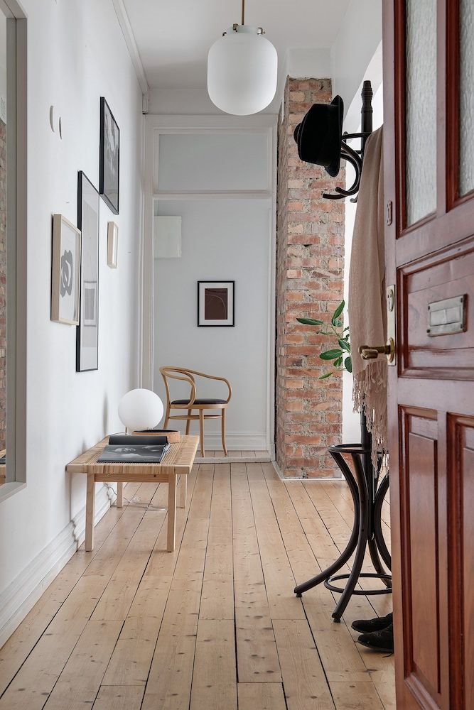 Pasillo de una casa moderna con cuadros y banco de madera