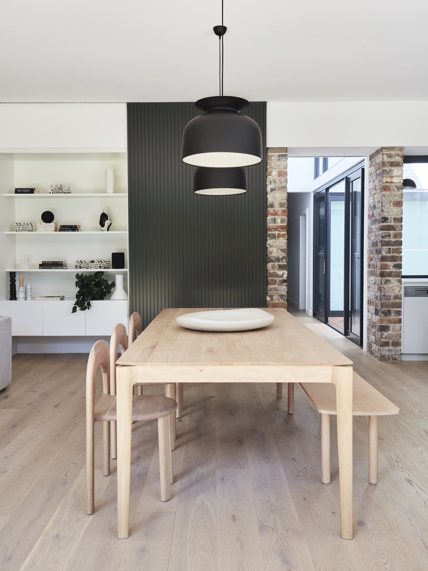 Casa moderna con paredes de ladrillo en Australia comedor con silal de madera