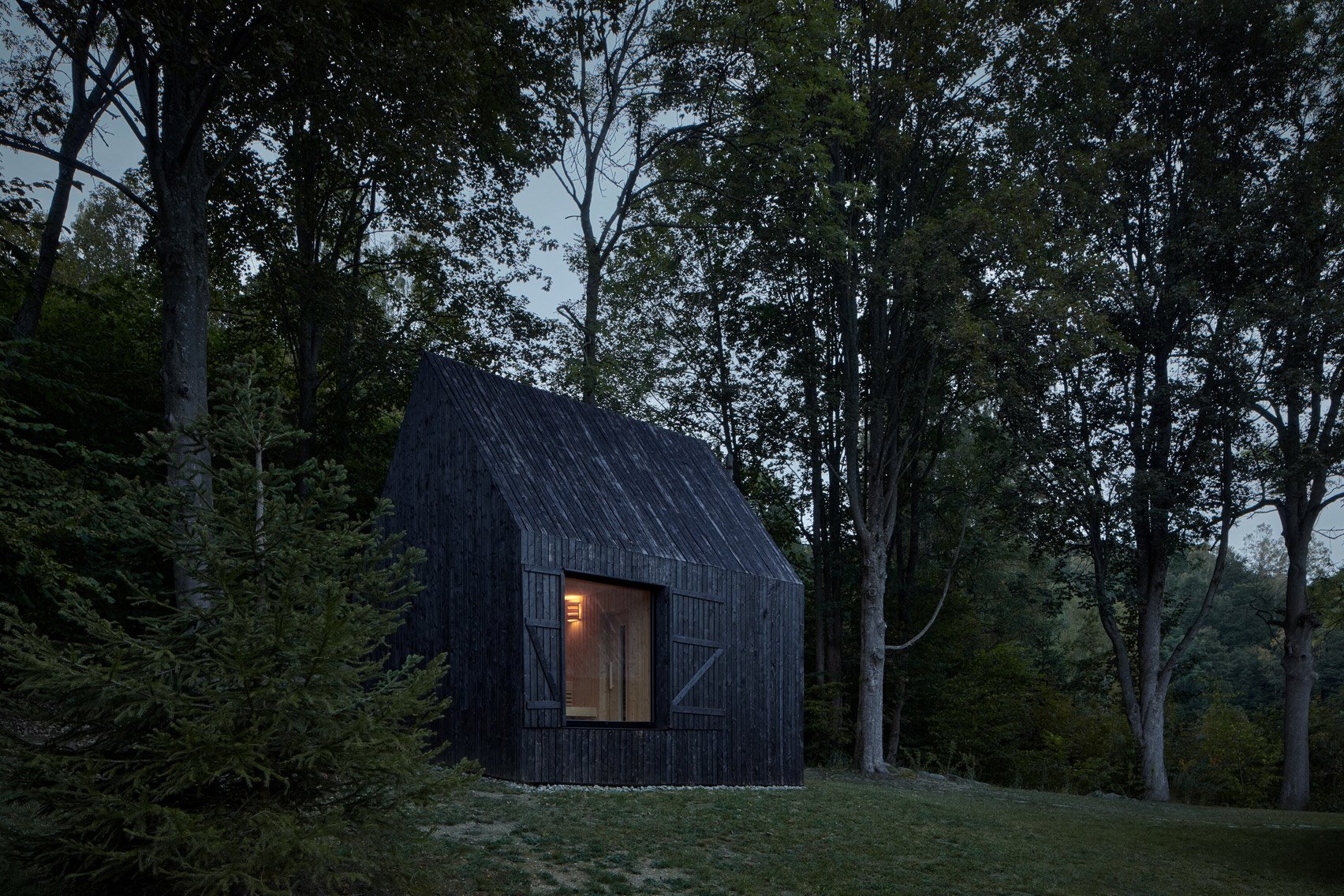 Casita de madera negra en el bosque de noche