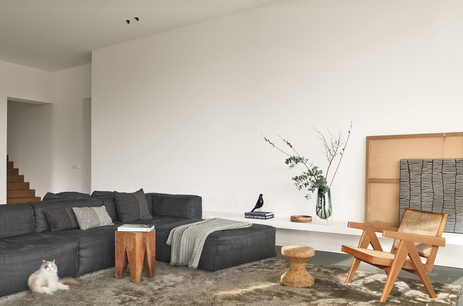 Salon con sofa gris oscuro y butaca de madera