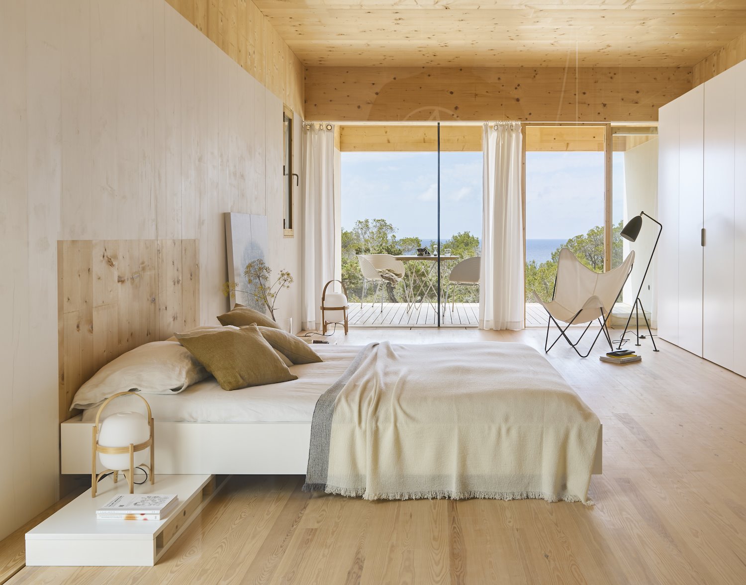 Dormitorio de una casa en madera natural con sabanas de lino y ventana