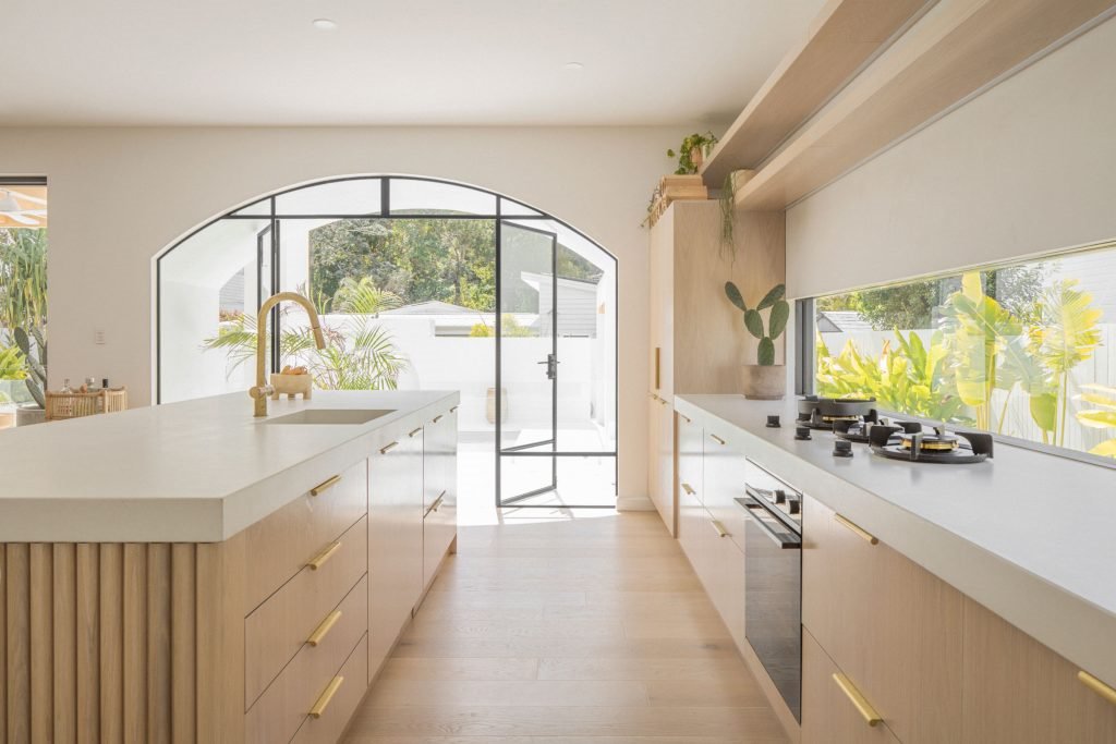 Casa junto a la playa de Australia con paredes blancas encaladas y decoracion moderna cocina abierta al jardin