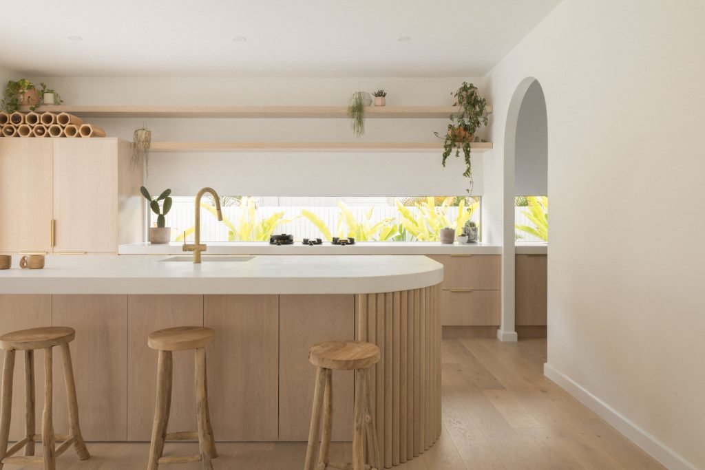 Casa junto a la playa de Australia con paredes blancas encaladas y decoracion moderna cocina con barra de madera