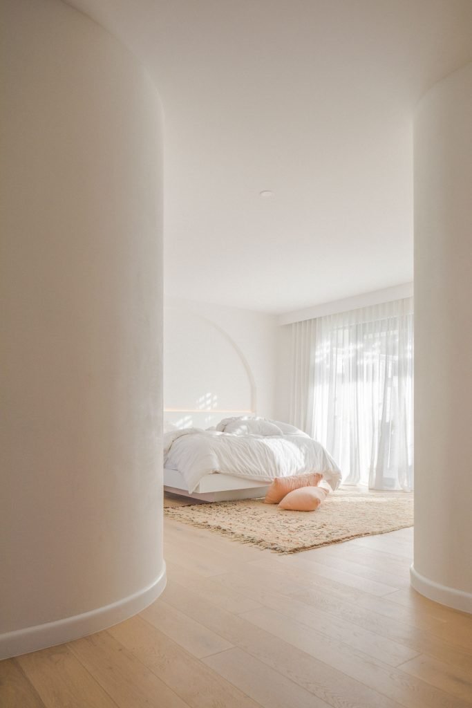 Casa junto a la playa de Australia con paredes blancas encaladas y decoracion moderna dormitorio con curvas