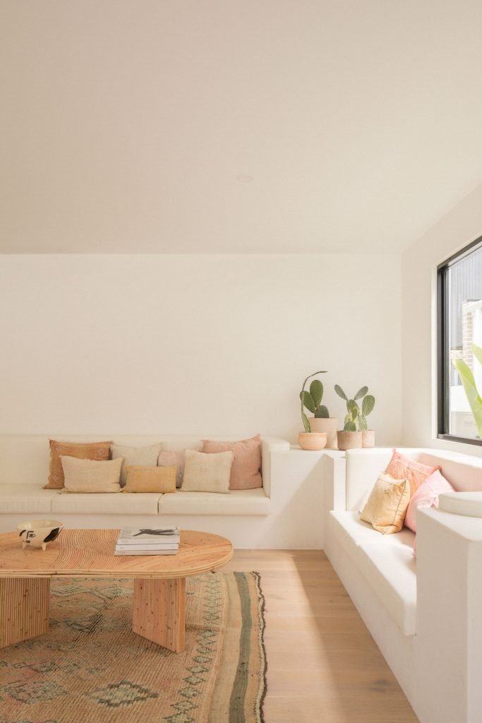 Casa junto a la playa de Australia con paredes blancas encaladas y decoracion moderna salon con cojines rosas