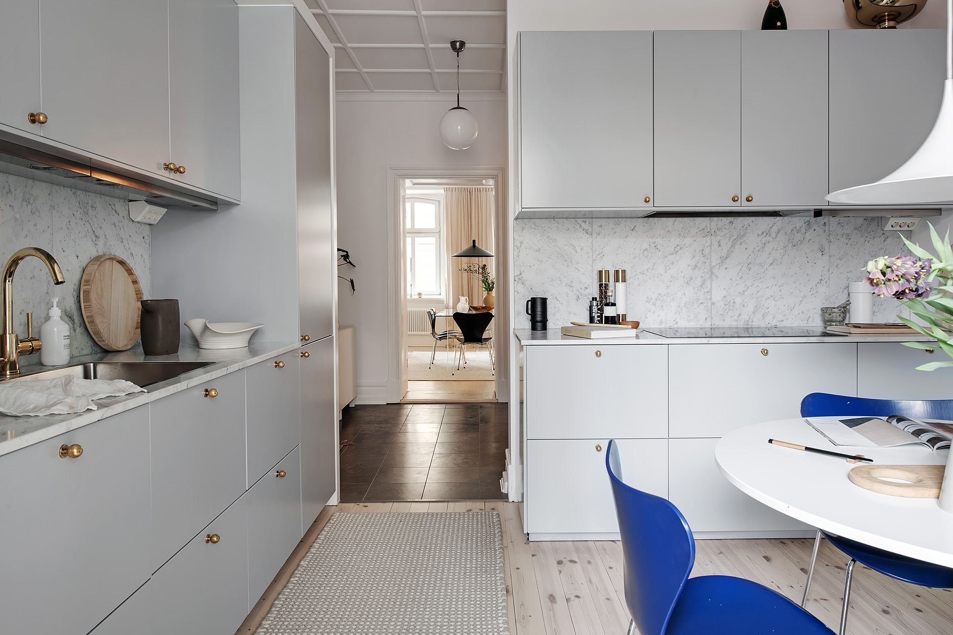 Piso con decoracion nordica moderna y paredes pintadas en color gris cocina comedor con sillas azules y lampara blanca