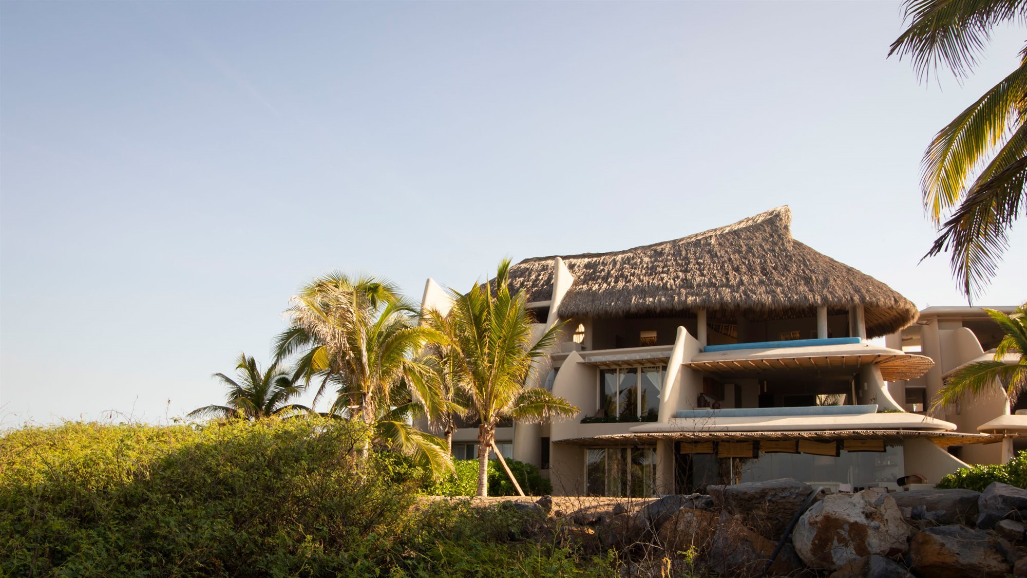 Casa en la playa con interiores de color ocre facahda con techo de paja