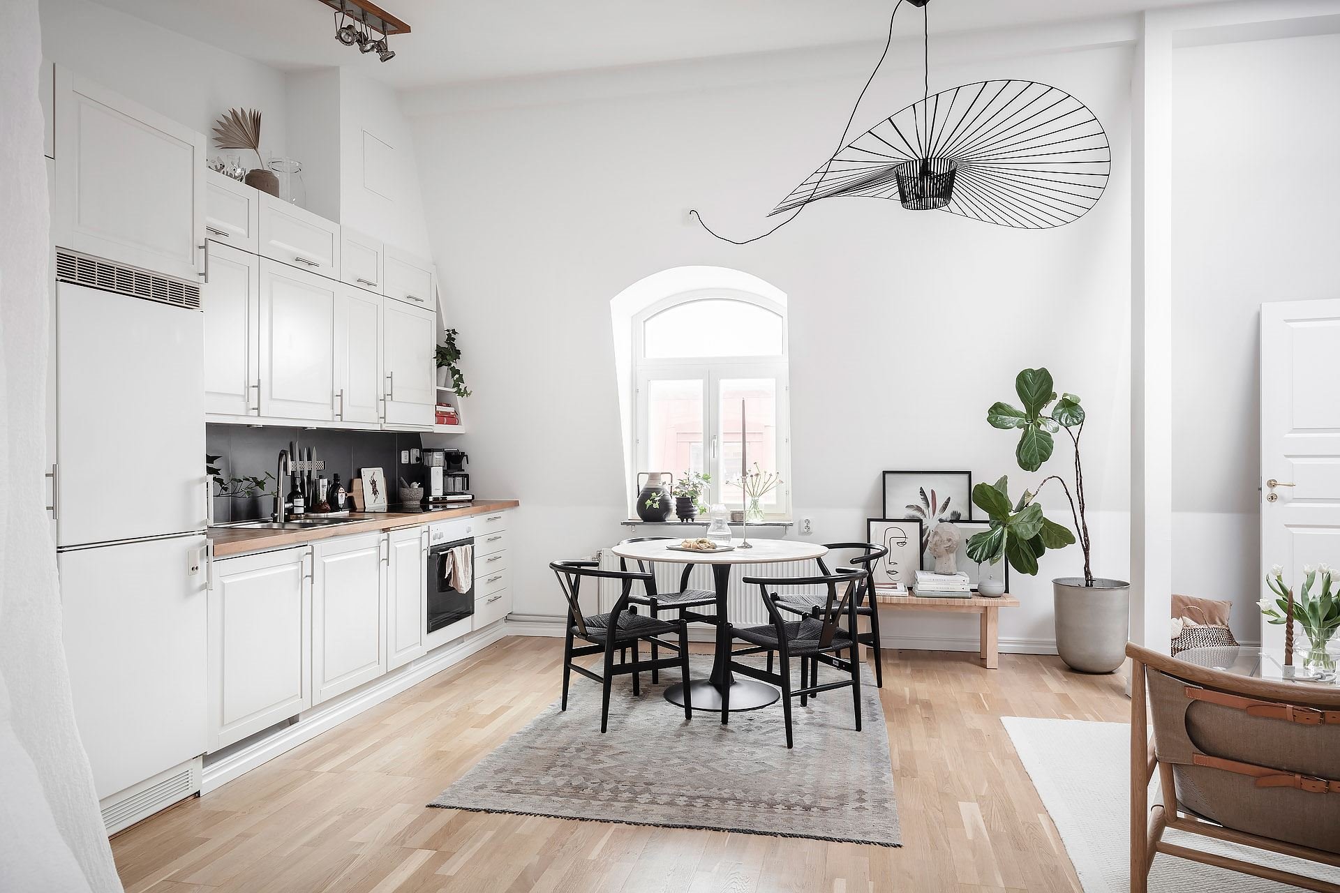 Piso con decoración nordica con columnas en el interiore y suelos de madera cocina comedor con lampara de alambre