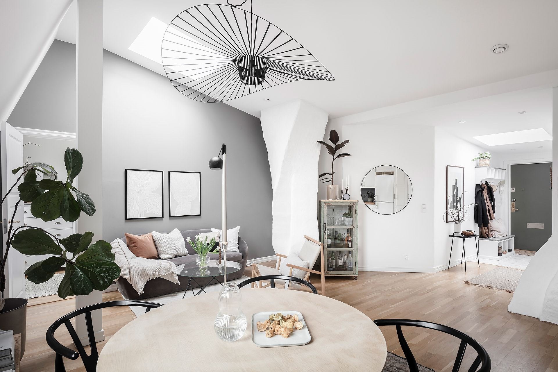 Piso con decoración nordica con columnas en el interiore y suelos de madera comedor con lampara de alambre