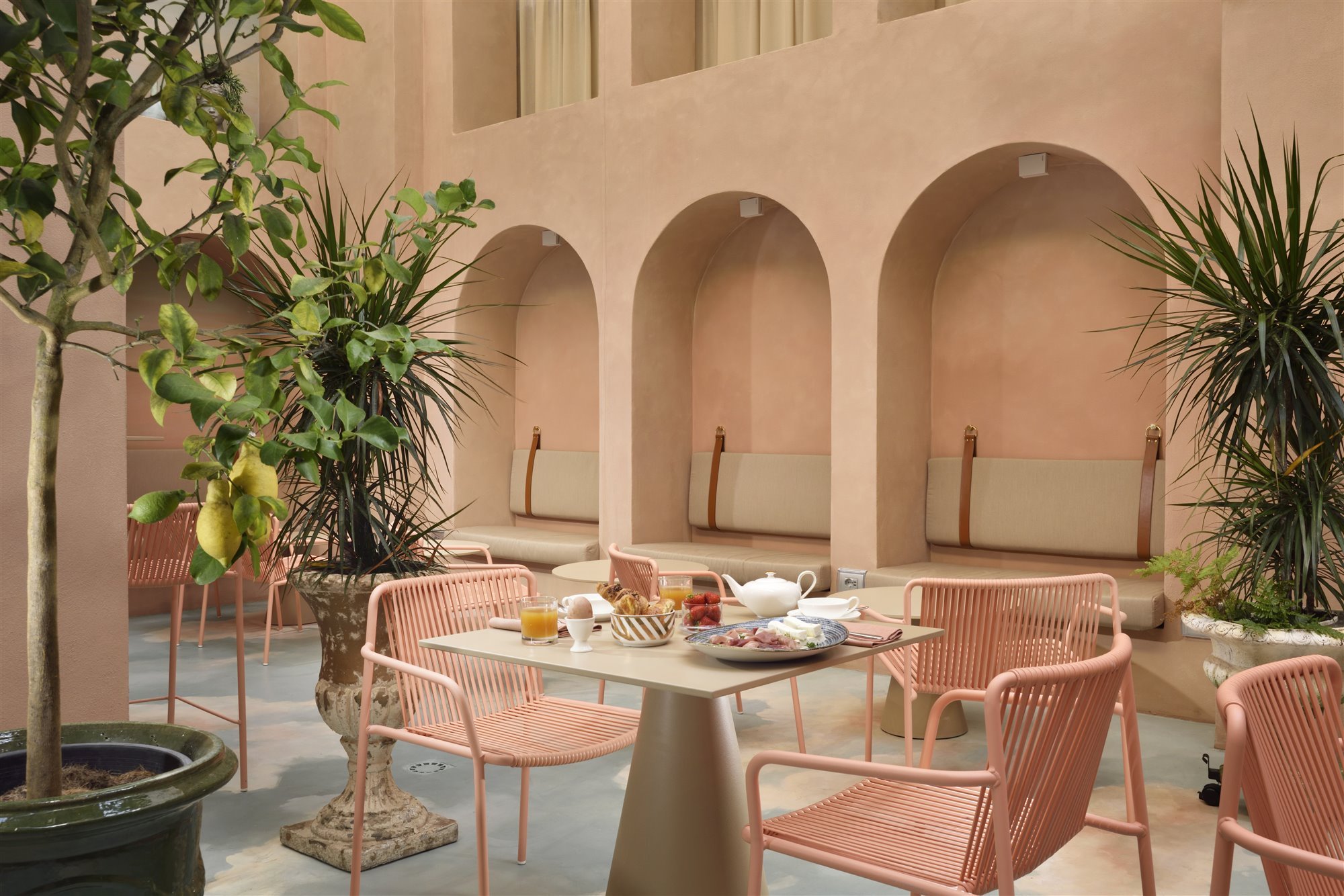 Patio con arcos de color rosa del hotel Leon Place en Roma 4