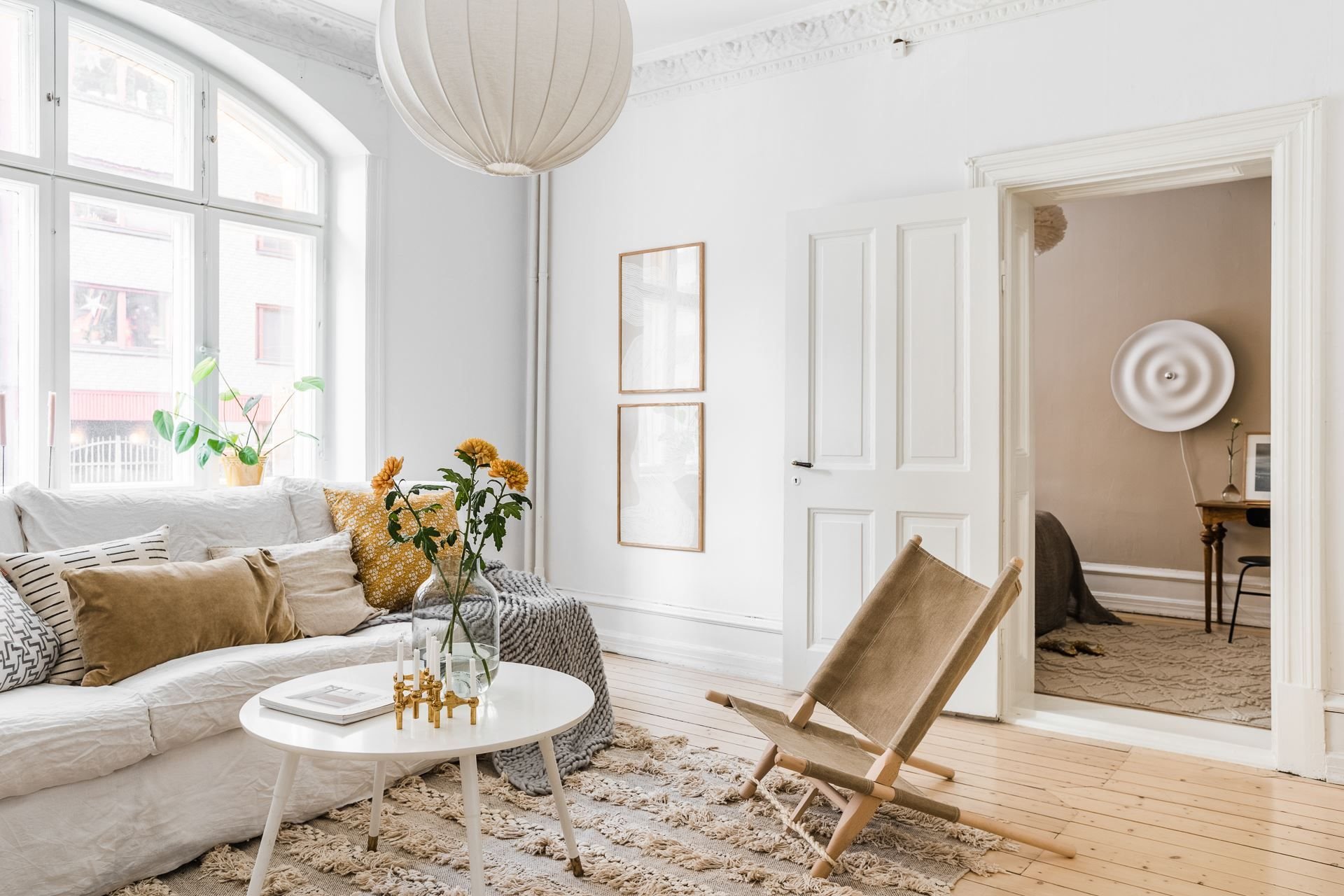 Salon con sofa de linio blanco alfombra y paredes de color blanco. Despeja la casa