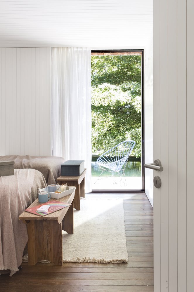 Dormitorio con banco a los pies de la cama de estilo rustico.