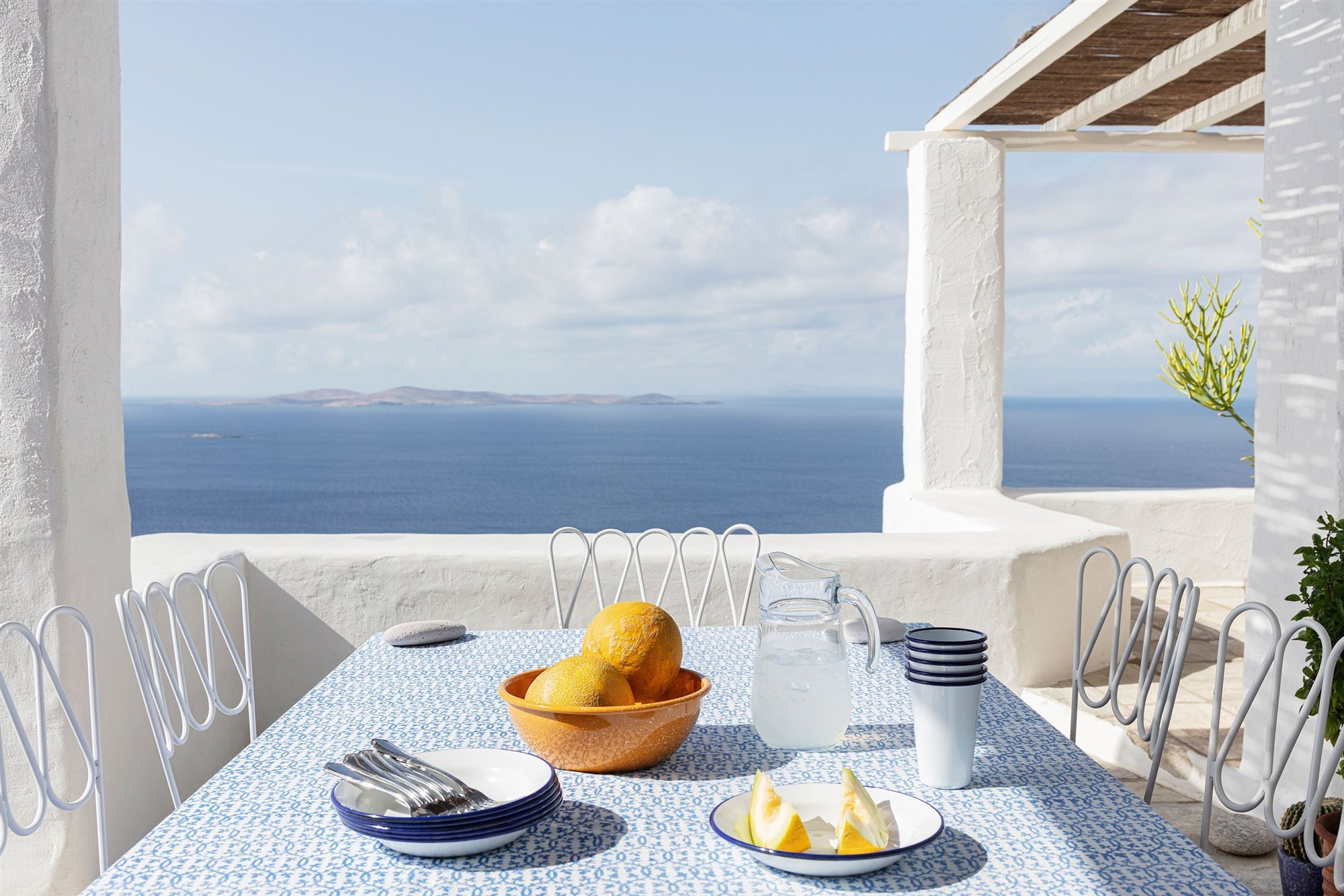 Casa de verano con fachada blanca en el mediterraneo en la isla de Mykonos comedor exterior con vistas al mar