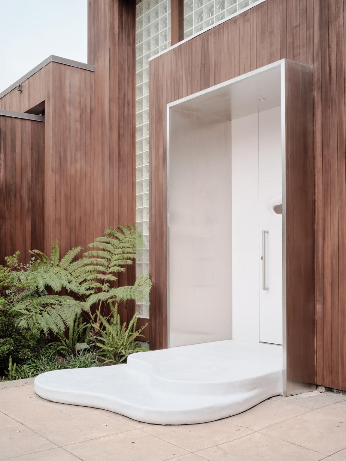 Casa en california con paredes organicas de color blanco puerta de entrada