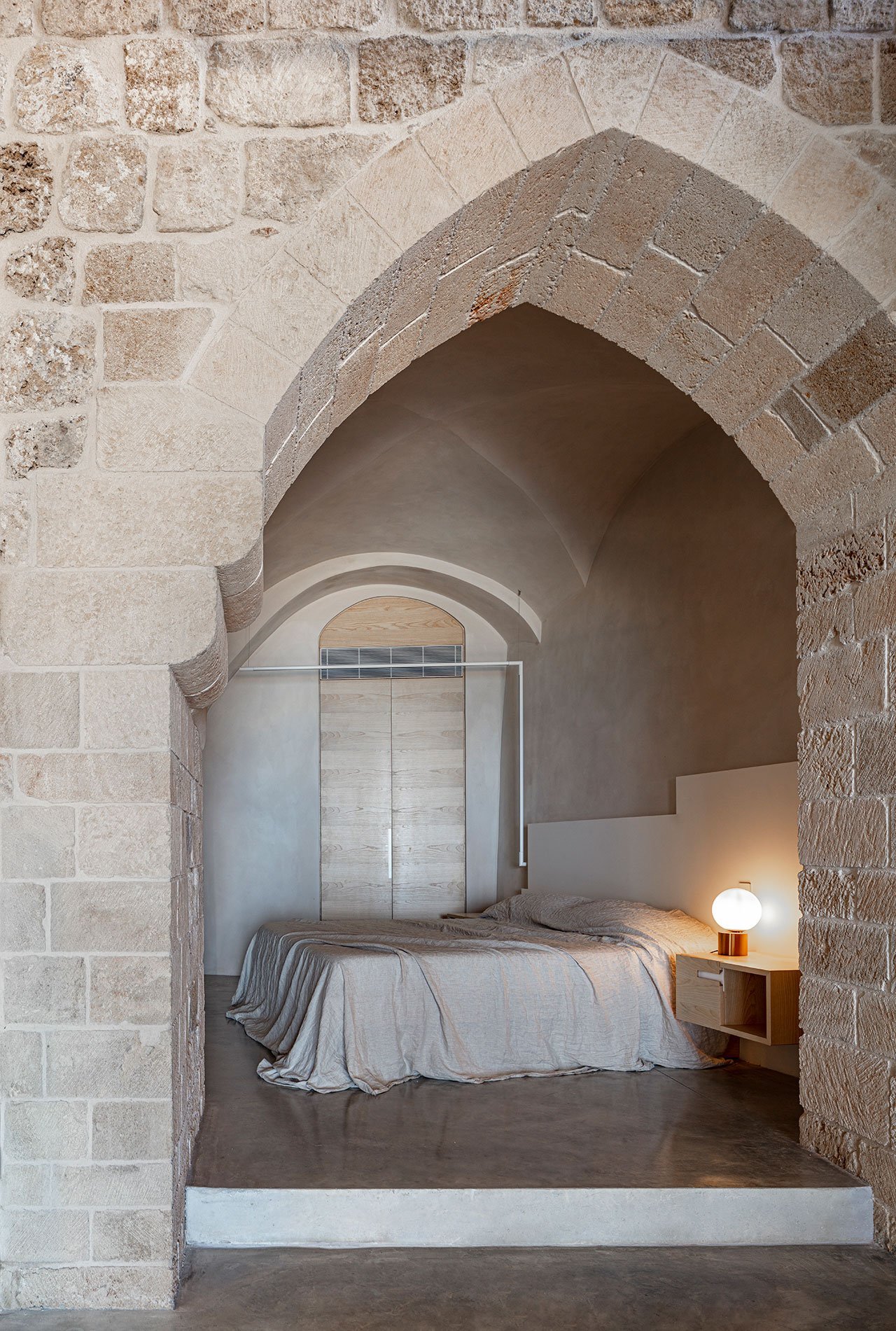Casa moderna de piedra y ladrillo reformada en Tel Aviv por el arquitecto Pitsou Kedem dormitorio bajo un arco