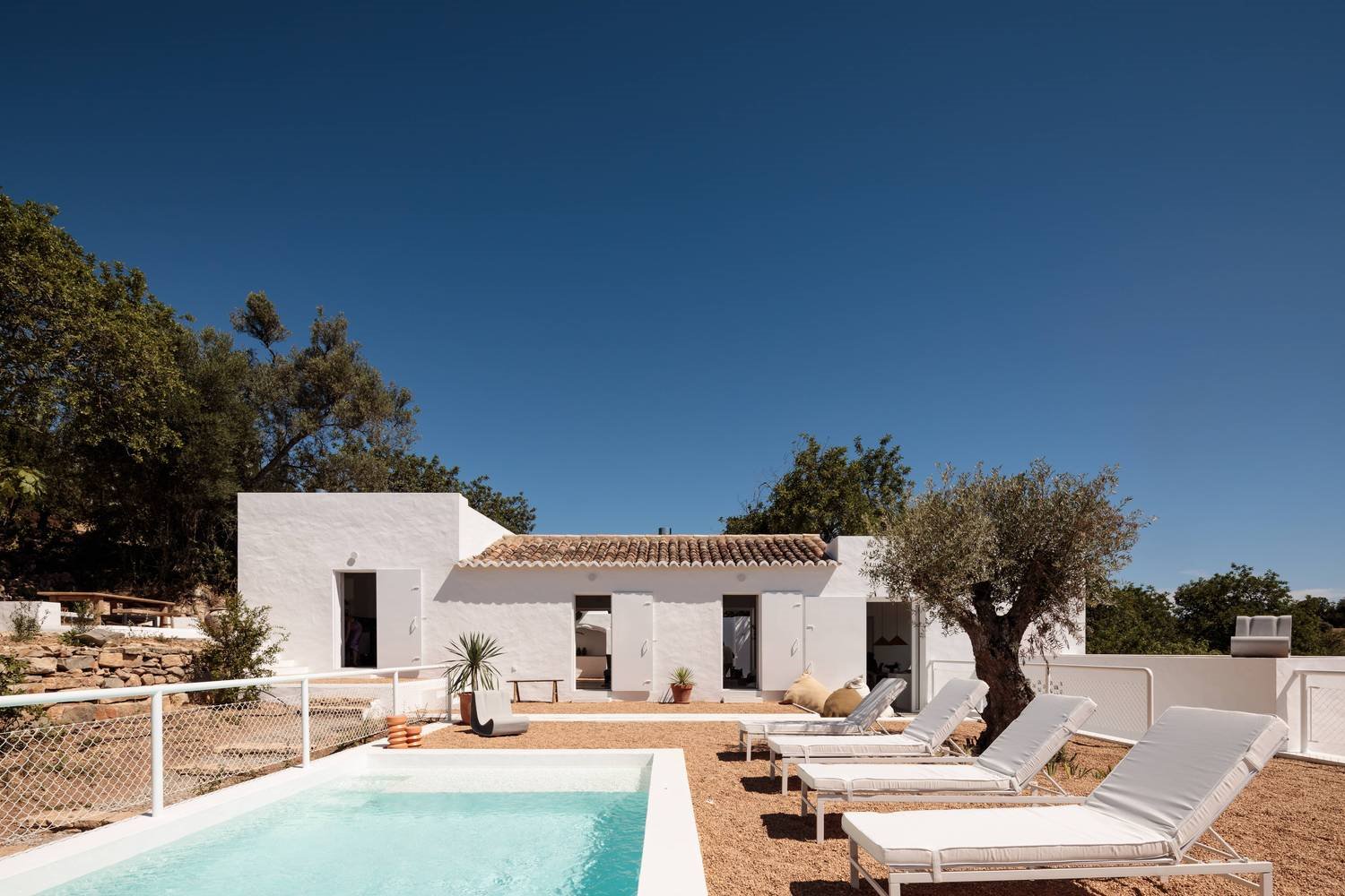 Casa de vacaciones en el algarve en Portugal con fachada e interiores de color blanco piscina con tumbonas