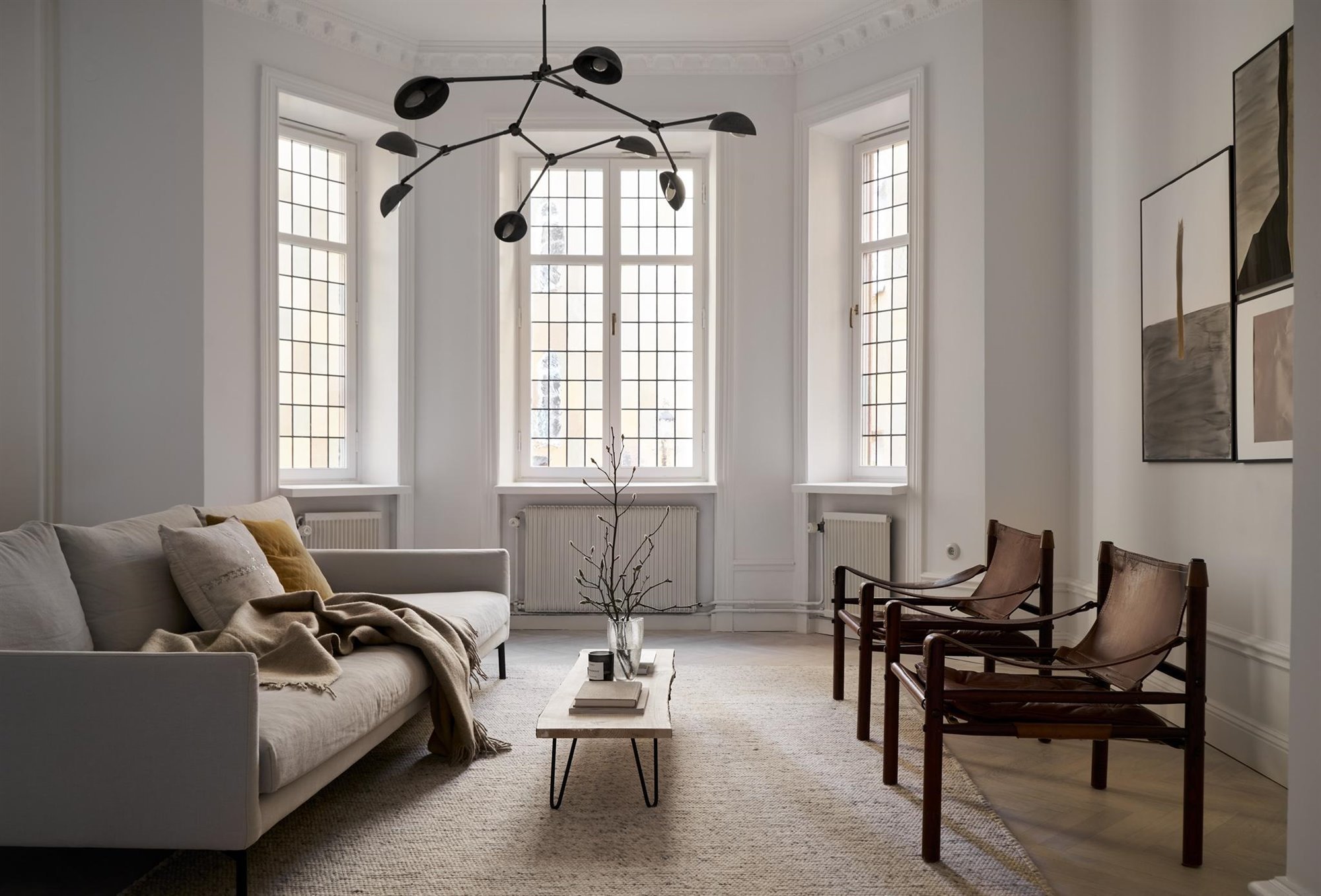 Piso con decoracion Nordica moderno con techos con molduras salon con sofa y butacas de piel