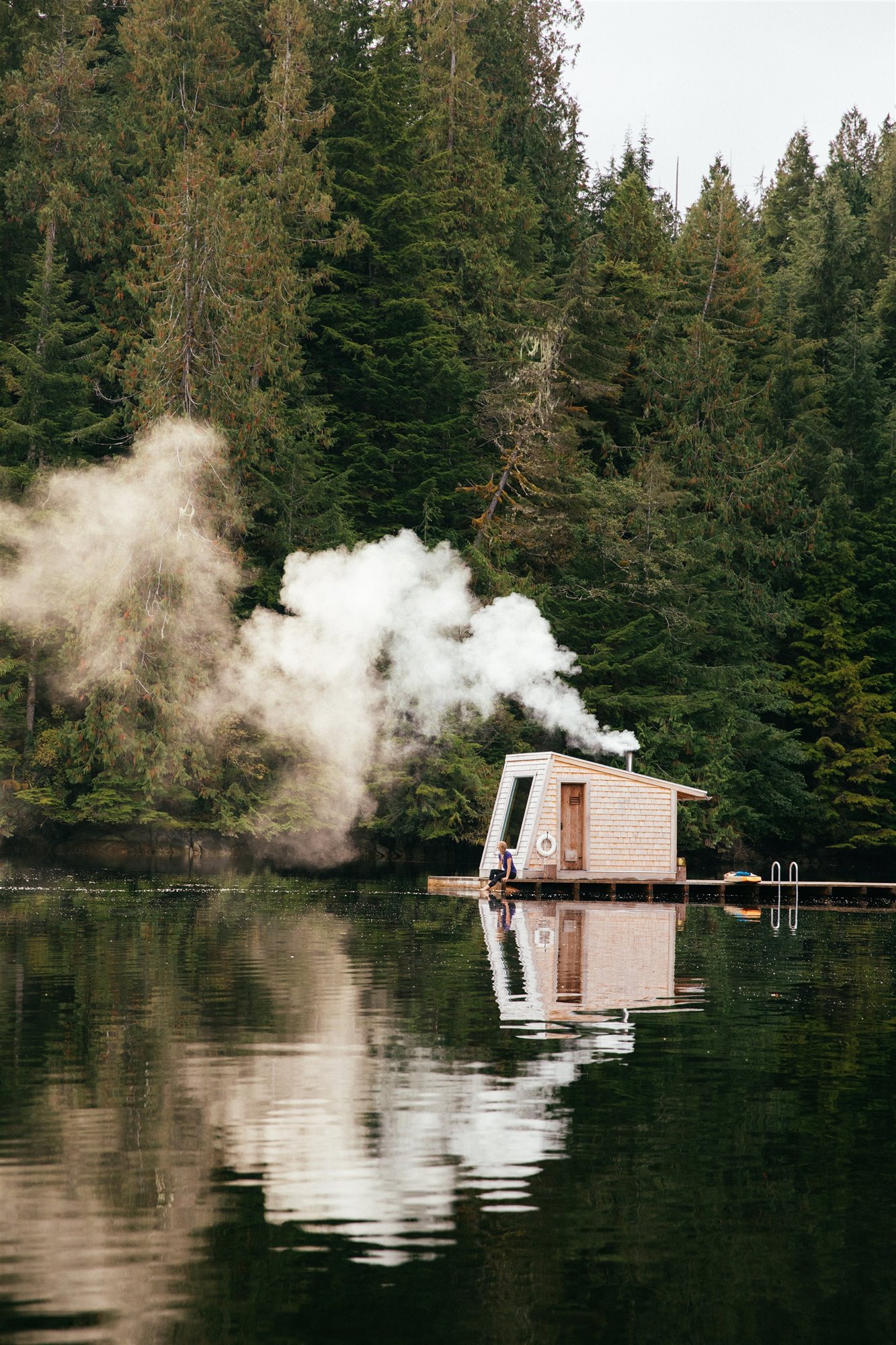 Cabaña moderna con Sauna de madera flotando en mitad de un lago con chimenea