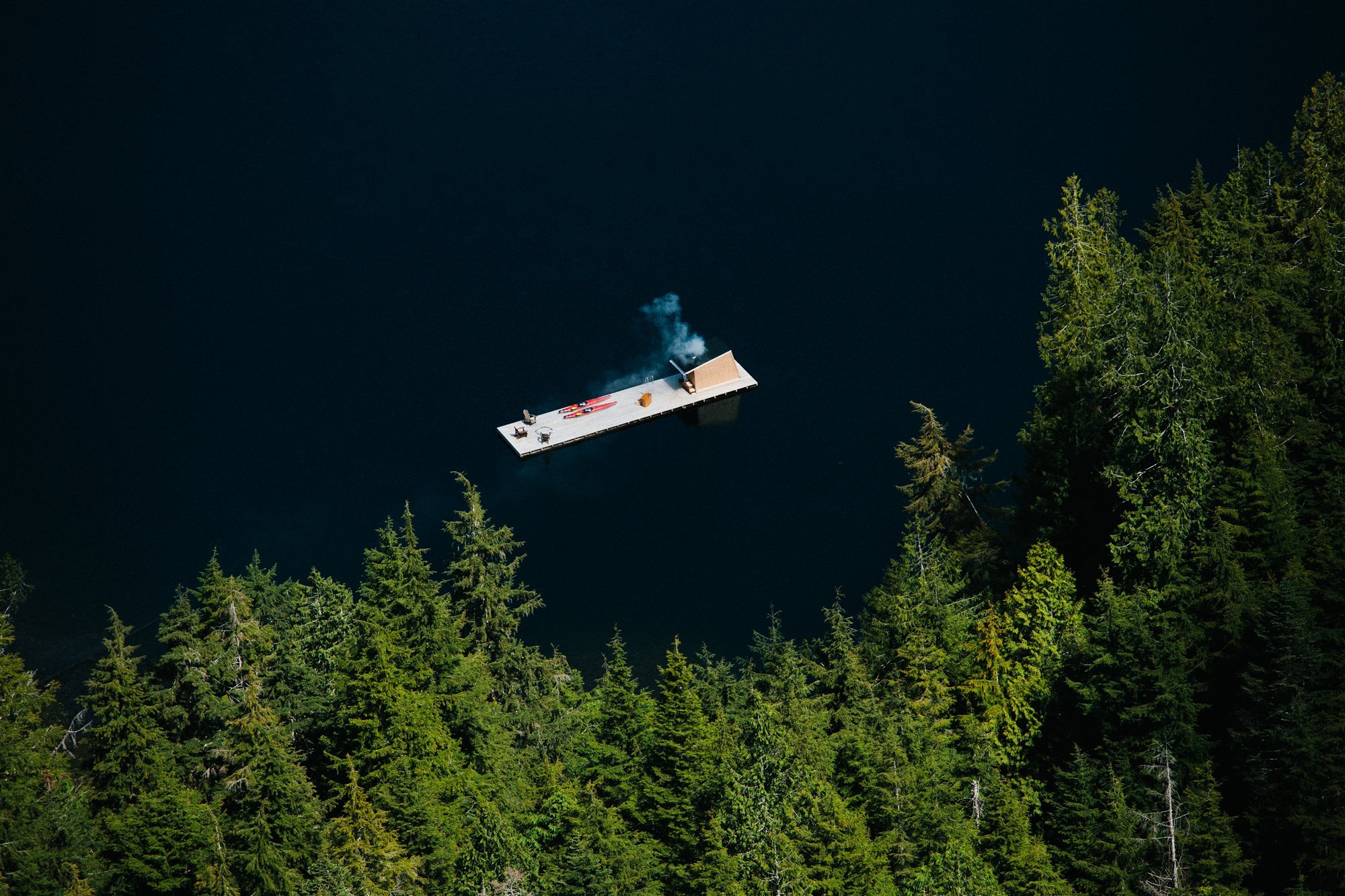 Cabaña moderna con Sauna de madera flotando en mitad de un lago junto a un bosque