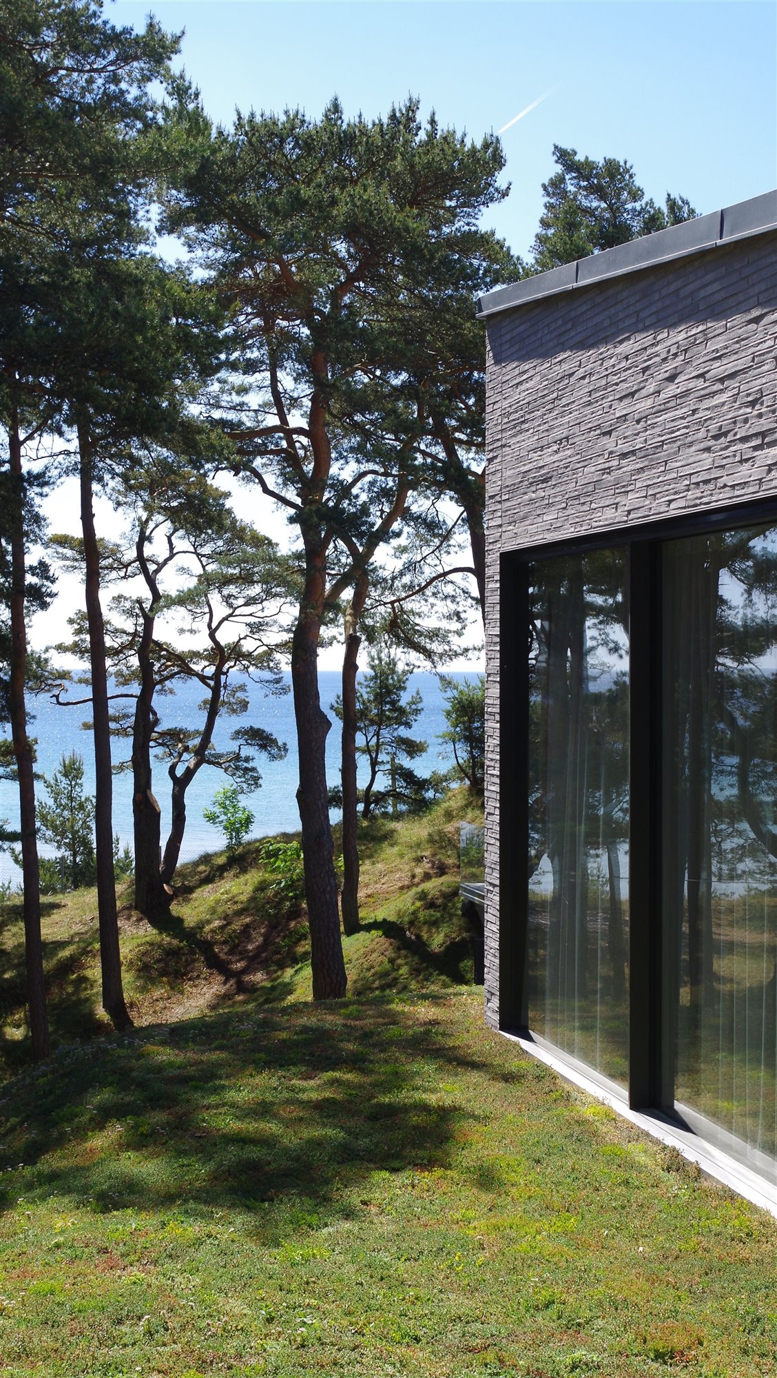 Casa moderna con fachada de piedra en mitad del bosque vistas