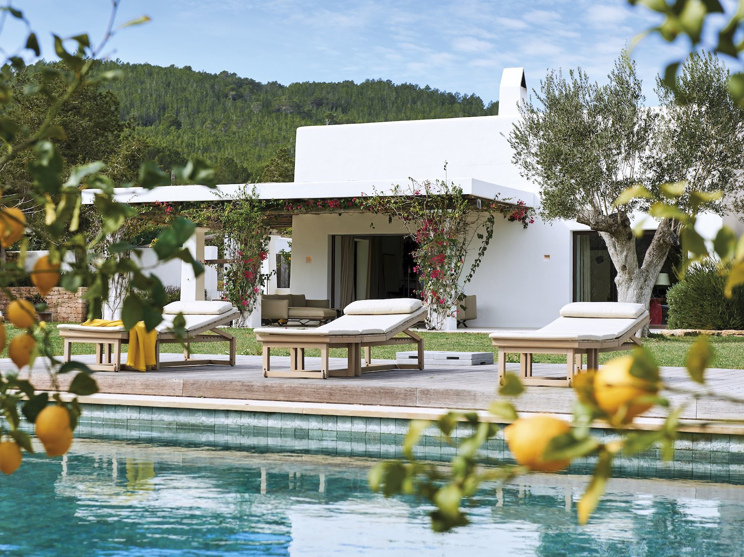 Casa con piscina con tumbonas de madera y colchoneta blanca