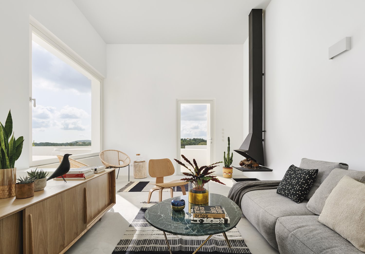 Salon con chimenea de color negro y sofa gris. Objetos decorativos