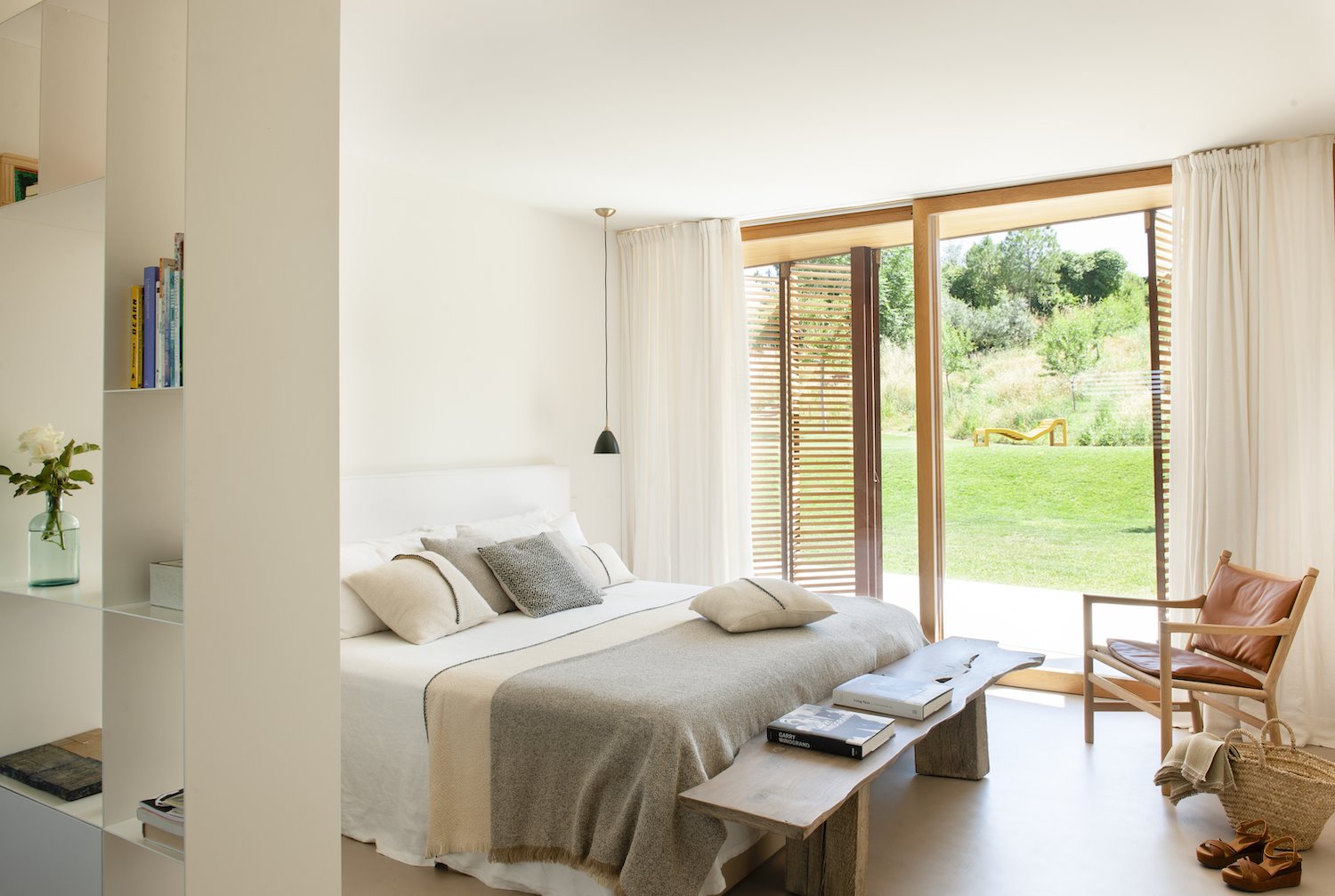 Dormitorio con ropa de cama natural y ventana abierta al jardin. La cama bien hecha