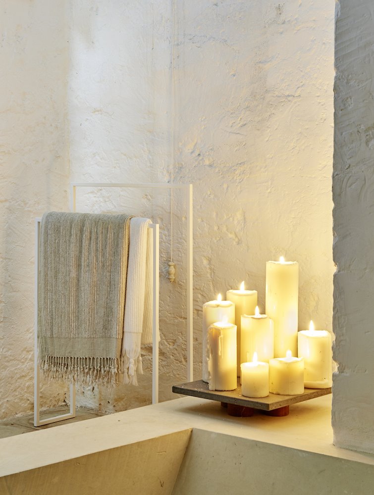 Velas encendidas en un baño moderno con paredes encaladas en blanco. Luz con vida