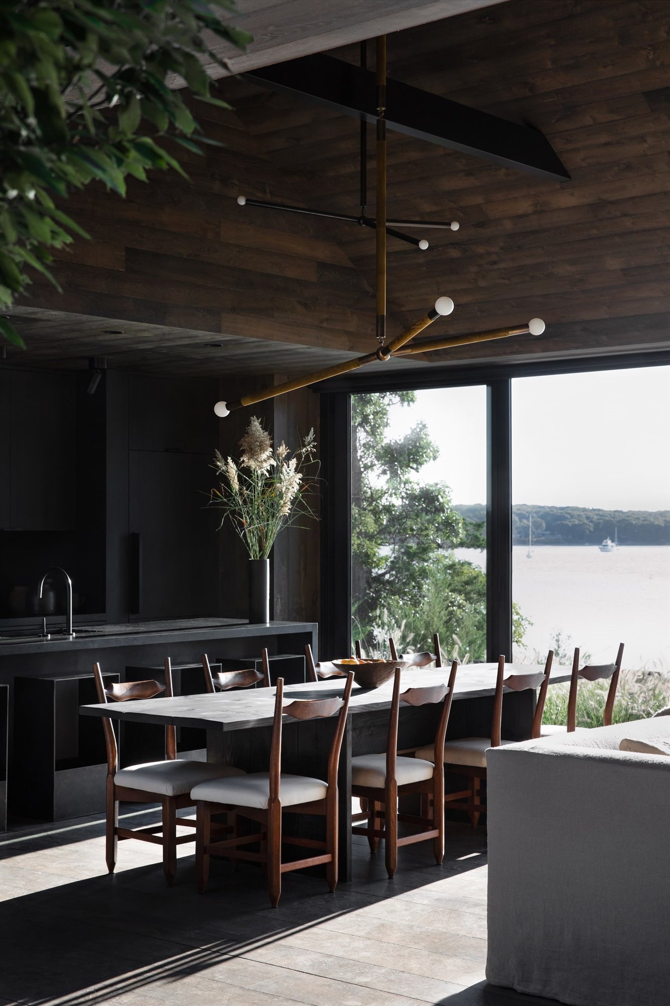 Casa en los Hamptons con fachada de madera en mitad del bosque comedor con vistas al lago