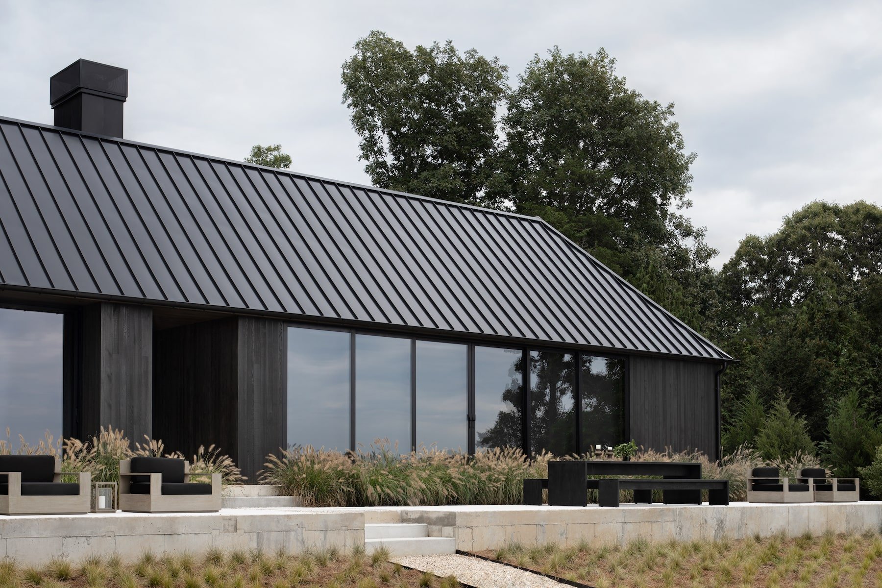 Casa en los Hamptons con fachada de madera en mitad del bosque fachada con puertas de cristal