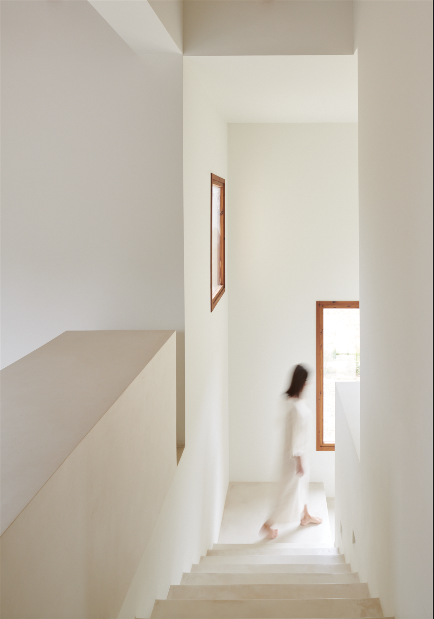 Pasillo con escalera de color blanco de una casa diseñada por el arquitecto Montis Sastre e interiorismo de Jorge Biblioni