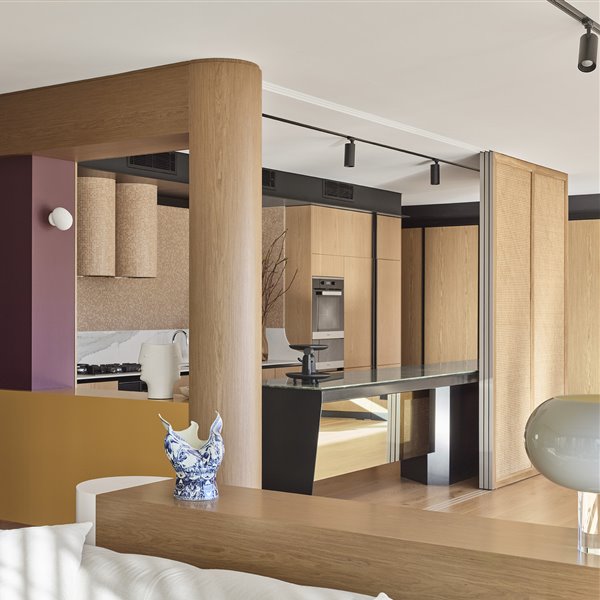 Unos paneles de ratán separan el comedor de la cocina en este piso de Australia con muebles a medida