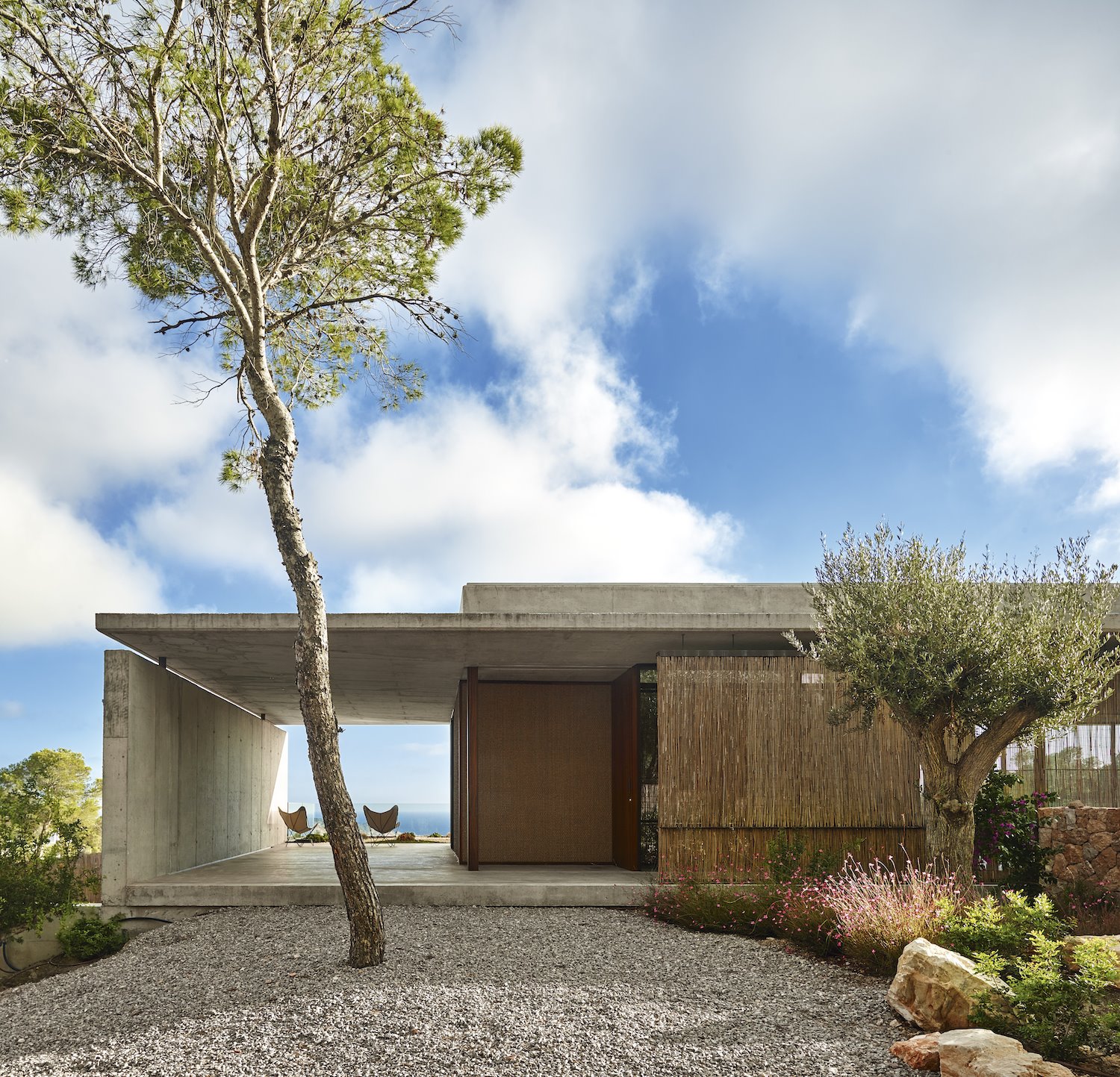 Fachada de una casa de hormigon con jardin exterior. La tierra