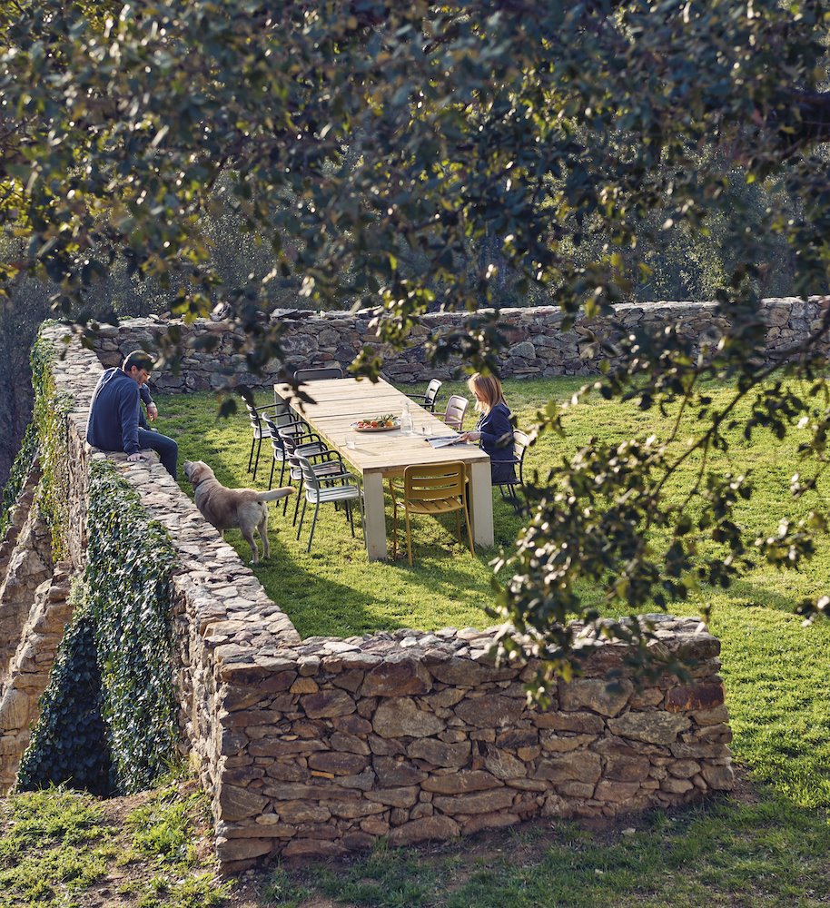 Vista aerea de un jardin con muro de piedra y comedor exterior. Los muebles