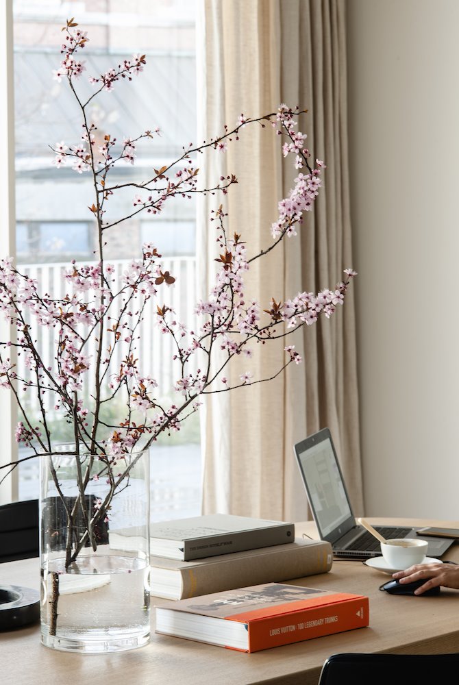 Mesa de trabajo con libros ordenador y un jarron con flores Foto Pere Peris