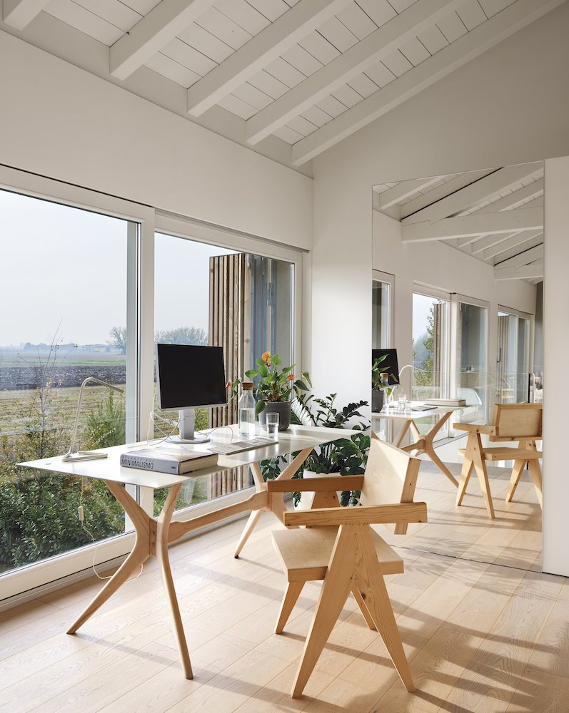 Estudio zona de trabajo con mesa de madera en una buhardilla con vigas de madera blancas Foto Eugeni Pons. Sin improvisación