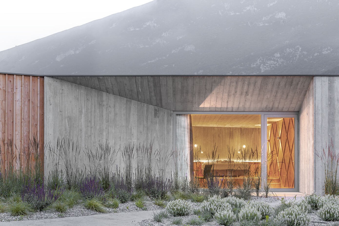 Casa de campo con fachada de madera rodeada de naturaleza acceso de hormigon