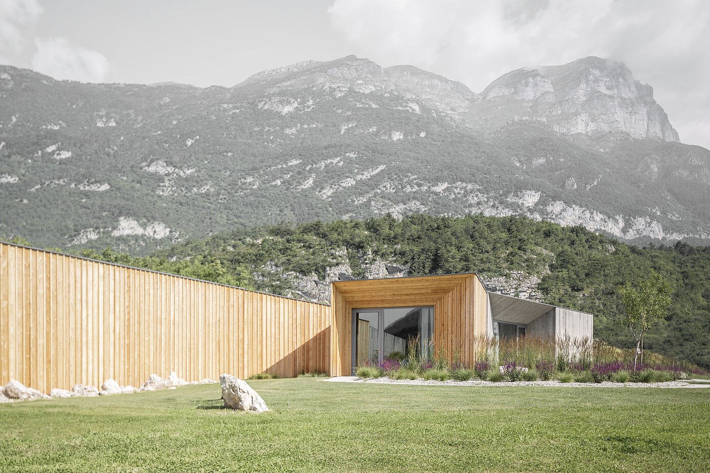 Casa de campo con fachada de madera rodeada de naturaleza en las montañas