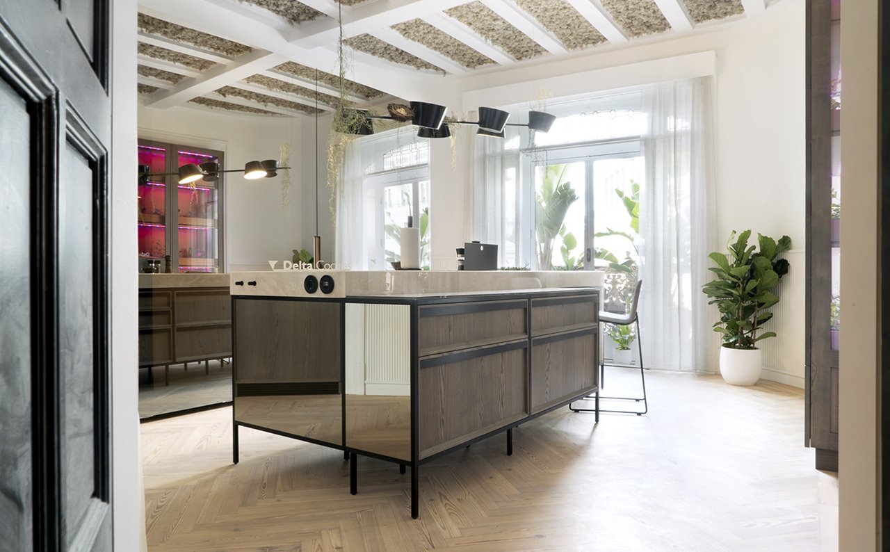La isla de cocina Argos protagoniza el espacio de Delta Cocinas en Casa Decor. Está realizada con puertas artesanales enmarcadas de madera de roble macizo acabado en fresno ahumado medio con tirador lineal metálico.