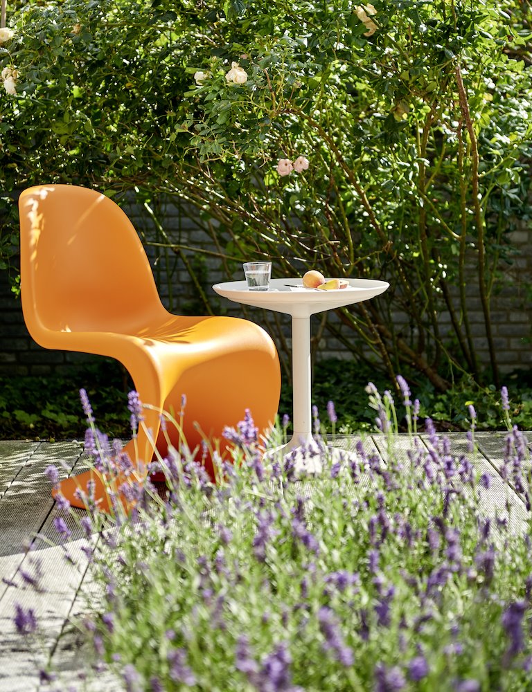 Mesa y silla de plástico con plantas de lavanda en un jardin