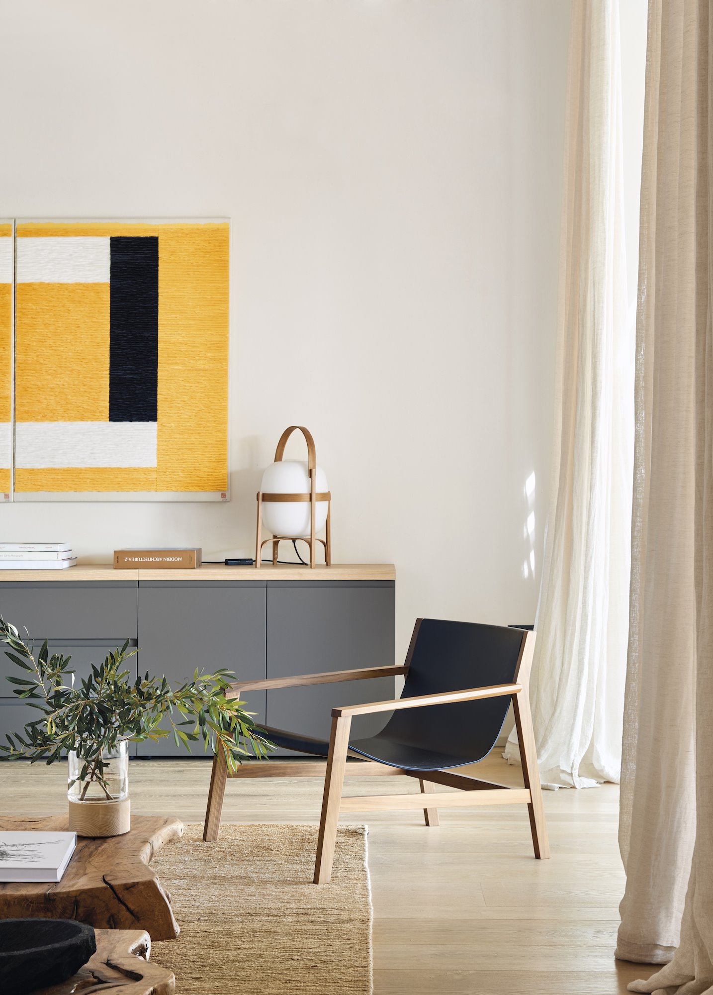 Silla de piel negra y madera y cortinas de lino crudo