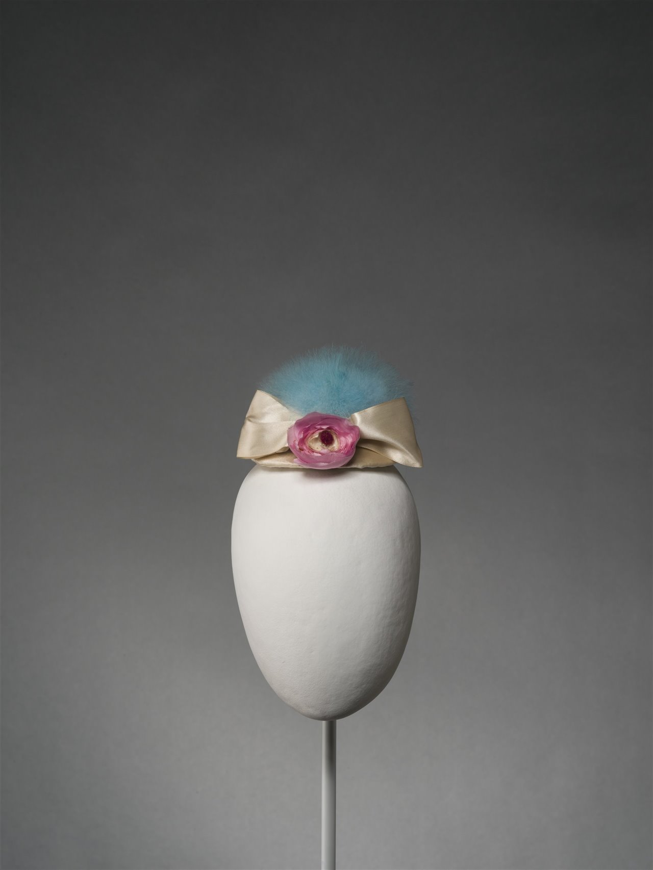 Nada en su trabajo es superfluo, ningún detalle es secundario. Un recuerdo es siempre una llave a su universo creativo. Tocado con un pompón de plumón de cisne teñido, cintas y tela de raso de seda, sobre estructura de esparterina