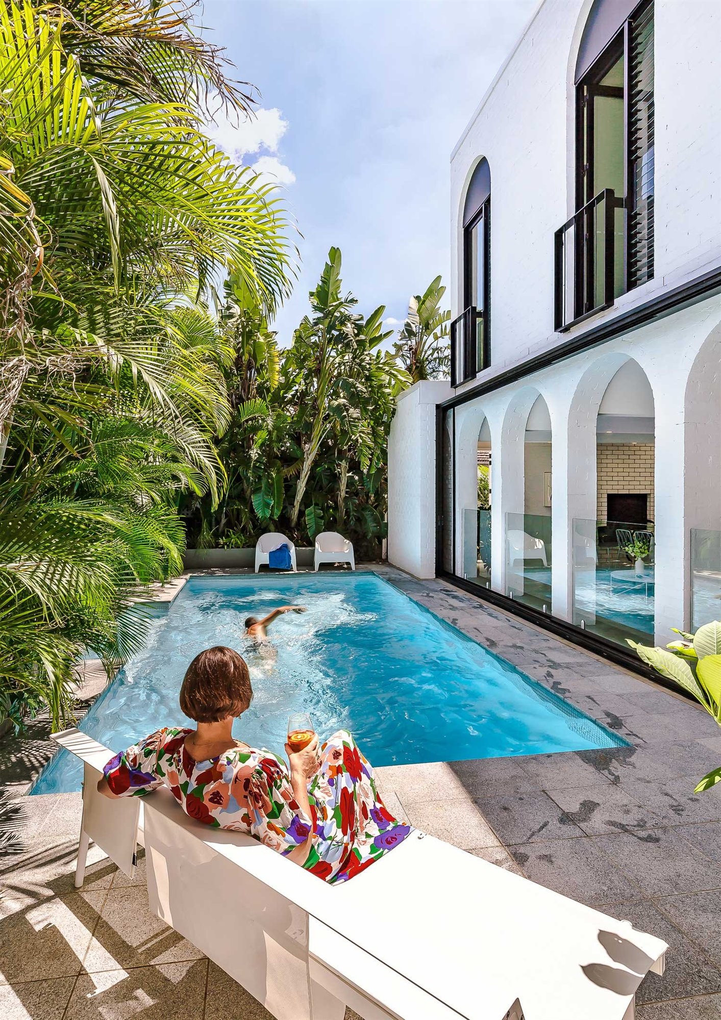 Casa de verano con piscina en Brisbane con fachada blanca con butacas blancas