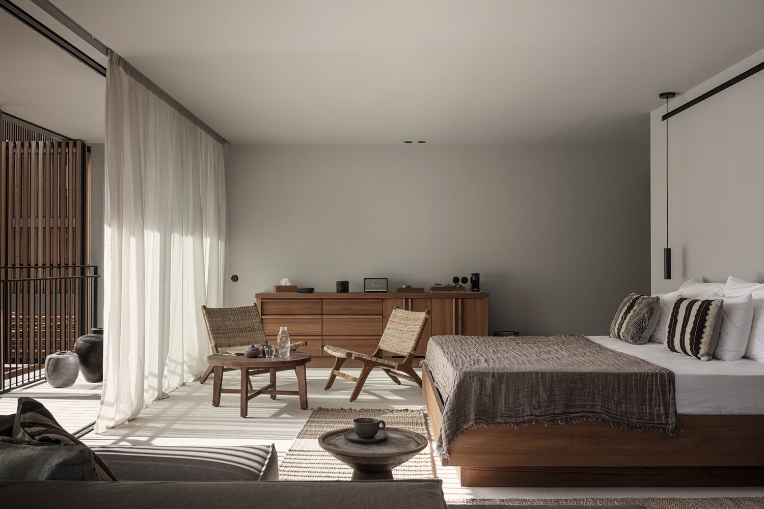 OKU suite con mobiliario en tonos tierra, colcha de lino y juegos de luz