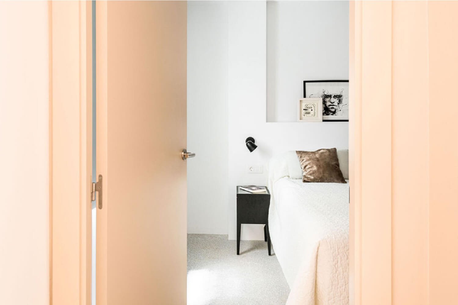 Dormitorio minimalista en color blanco y con puerta rosa