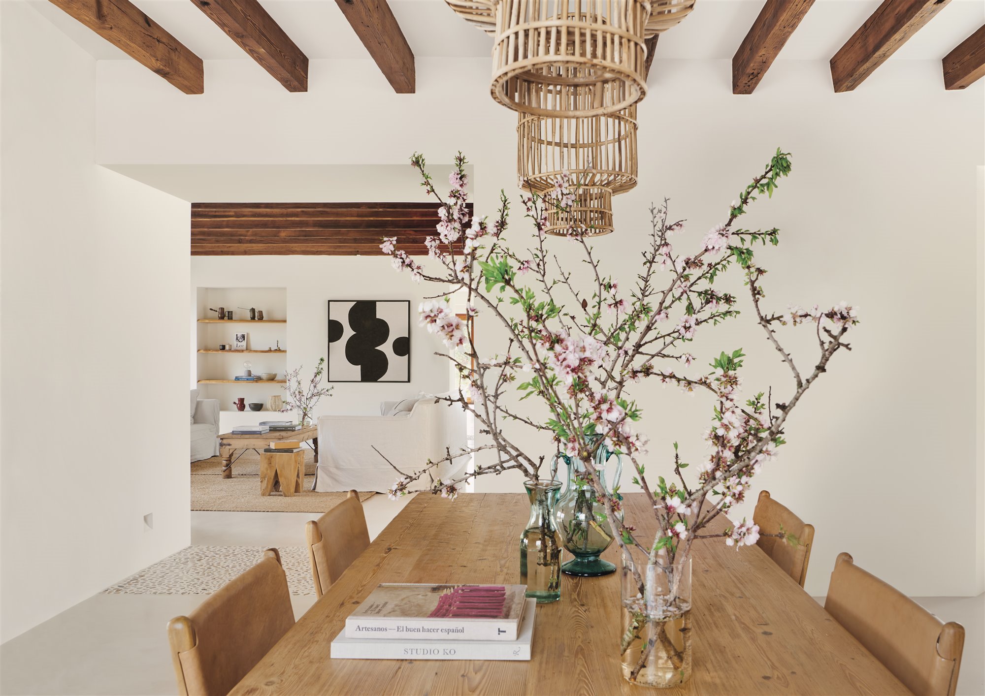 Comedor de una casa moderna con mesa de madera y jarrones con flores de cerezo